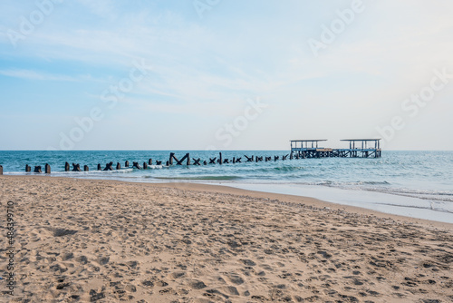 beach with abandoned ruin pier over blue sea and sky
