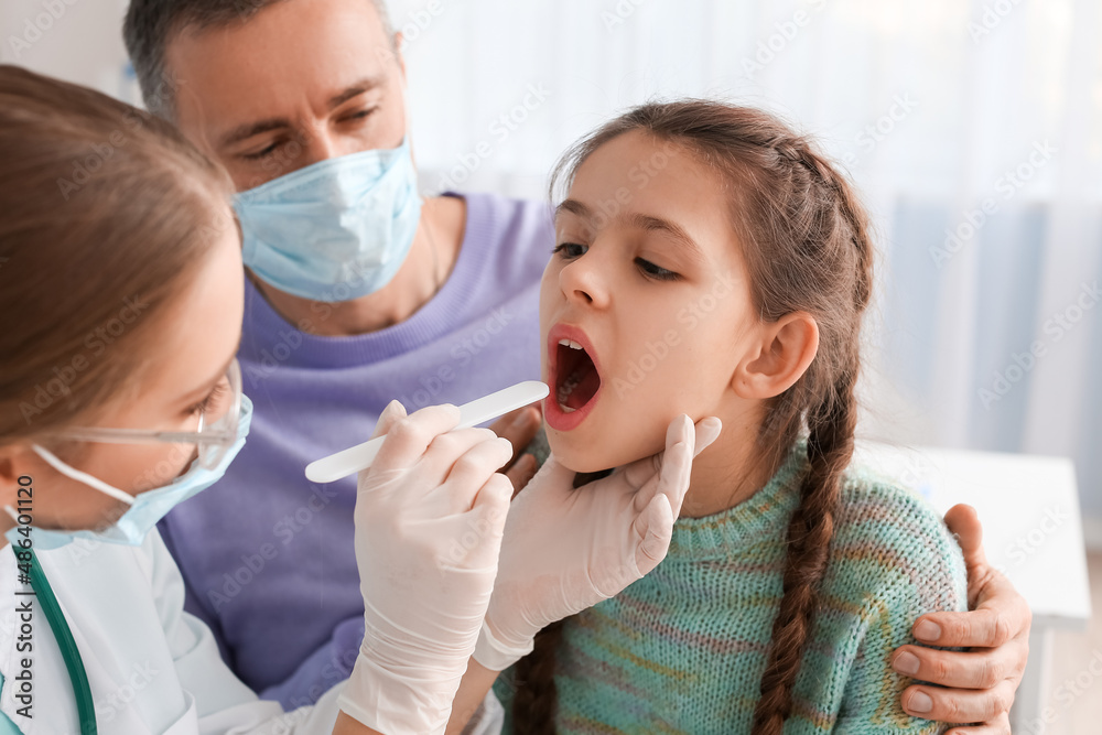 Doctor examining little girl with sore throat in clinic Doctor examining little girl with sore throat in clinic