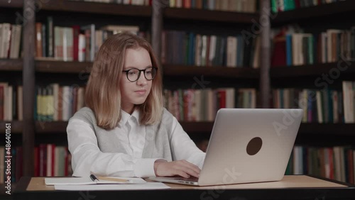 Shocked schoolgirl staring at the laptop screen, saw unexpected news, amazed and surprised looking at monitor with mouths opened she closed laptop in Library