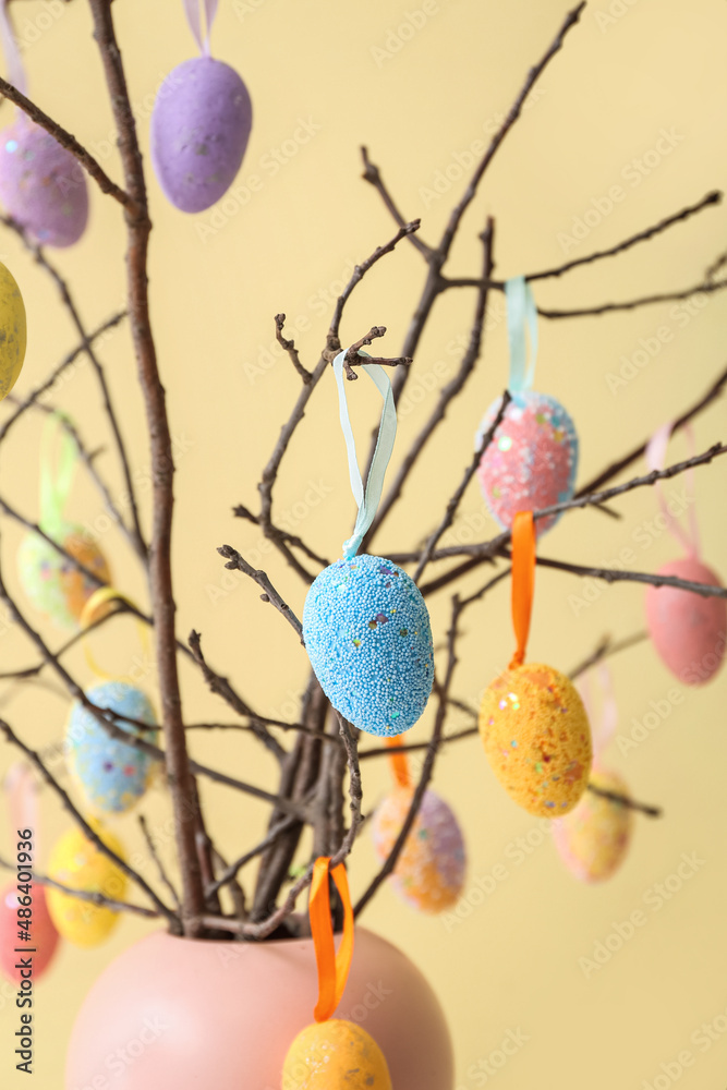 Composition with Easter eggs hanging on tree branches against color background, closeup