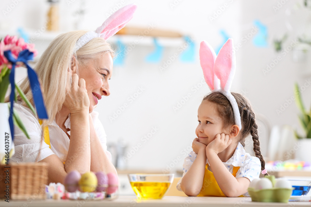 Little girl and her grandmother with bunny ears during painting of Easter eggs at home Little girl and her grandmother with bunny ears during painting of Easter eggs at home