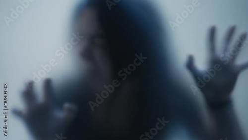 Person in pain behind glass woman suffering from depresson concept feeling trapped defocused shot photo