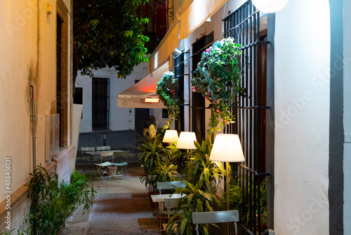 Fototapeta Naklejka Na Ścianę i Meble -  A narrow side street with tables from a cafe in the Barrio Santa Cruz district of Seville, Spain.