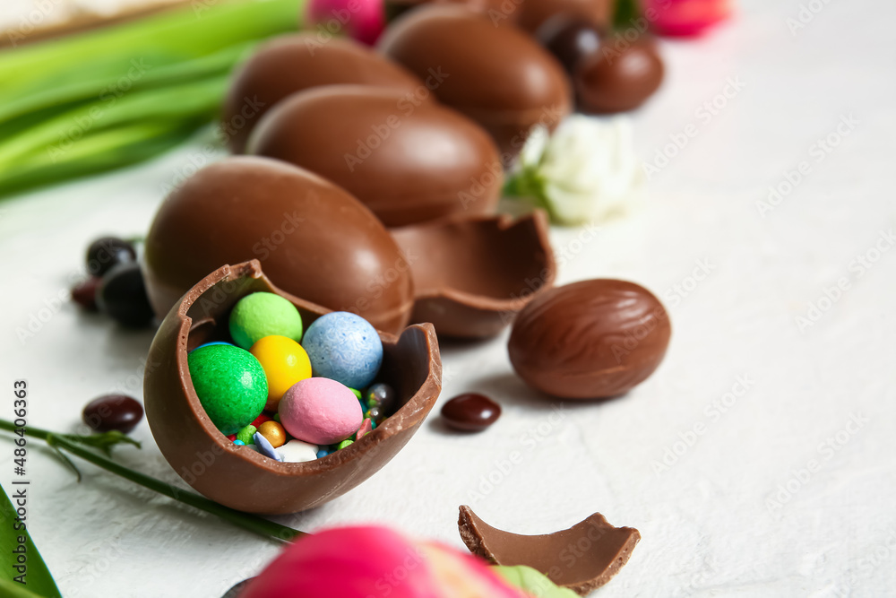 Broken chocolate Easter egg with different candies on light background, closeup Broken chocolate Easter egg with different candies on light background, closeup