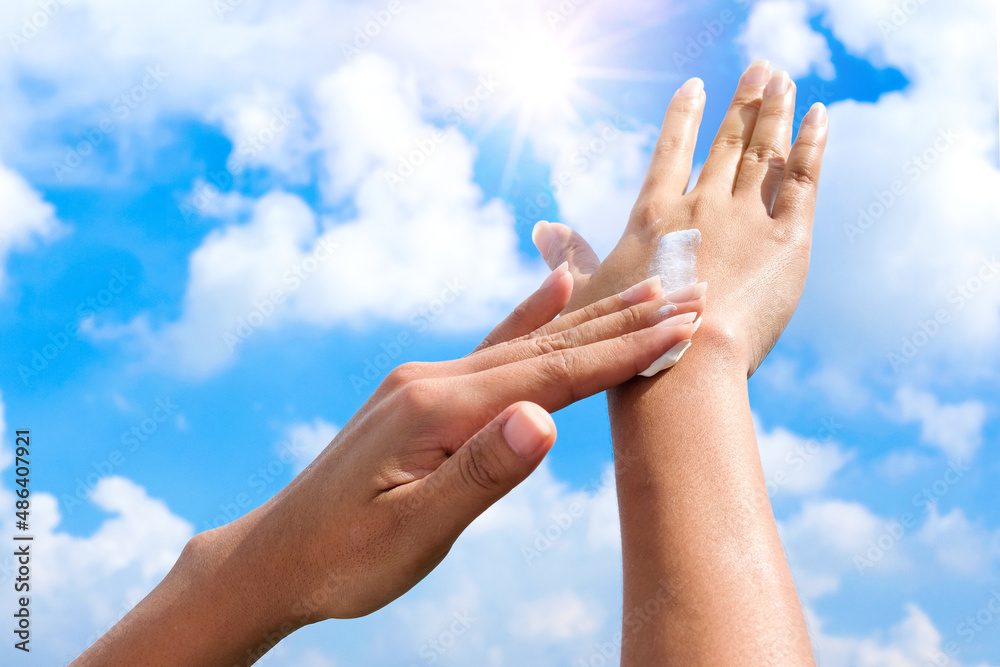 Hand of female holding sunscreen. Very sun light Sky background.Health concepts and skin care Hand of female holding sunscreen. Very sun light Sky background.Health concepts and skin care