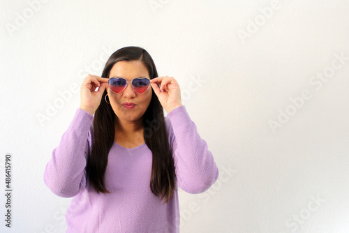 Latin adult woman with heart-shaped sunglasses shows enthusiasm for February and celebrate Valentine s Day of Love and Friendship with partner  friends and family 