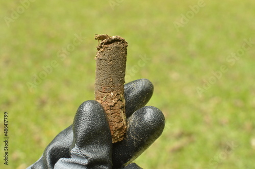 Fotografija Holding lawn soil core from aerator after lawn core aeration