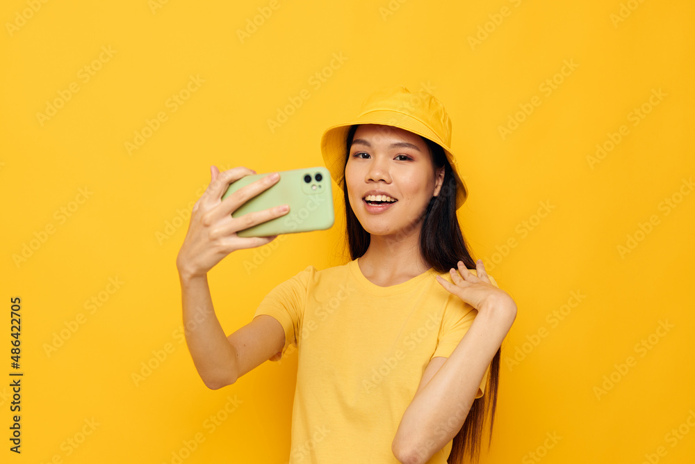woman with Asian appearance talking on the phone posing fashion yellow background unaltered