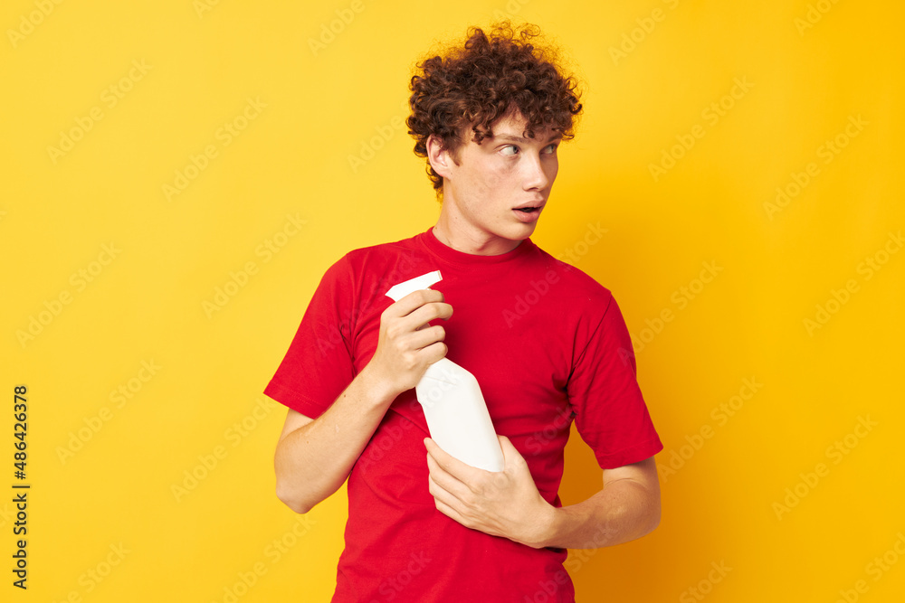Young curly-haired man in a red t-shirt detergents in hands posing Lifestyle unaltered Young curly-haired man in a red t-shirt detergents in hands posing Lifestyle unaltered
