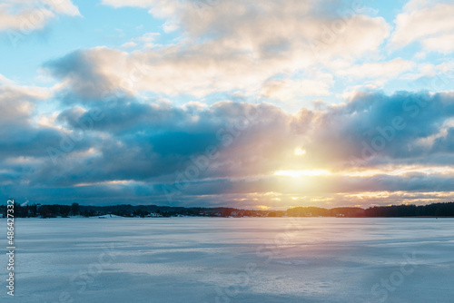 Beautiful winter sunset over the frozen lake. Ice with sunset reflections in the foreground cloudy sky winter.