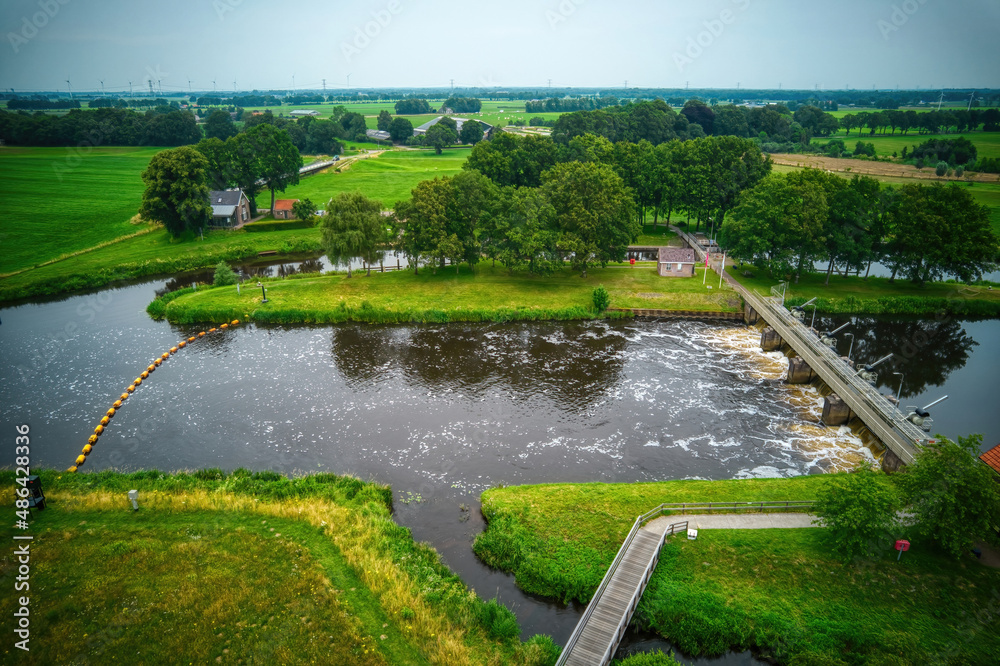 Drone view of the river Vecht, green grass, trees, beautiful blue sky and cycle path through the Vecht valley. Bridge and weir in the river. Dalfsen Netherlands