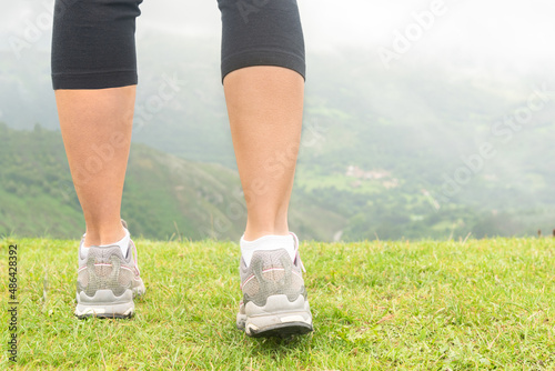 Crop woman in sneakers on edge of hill