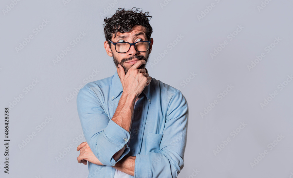 young man wondering with his hand on his chin on an isolated background, a guy thinking with his hand on his chin. young man wondering with his hand on his chin on an isolated background, a guy thinking with his hand on his chin.