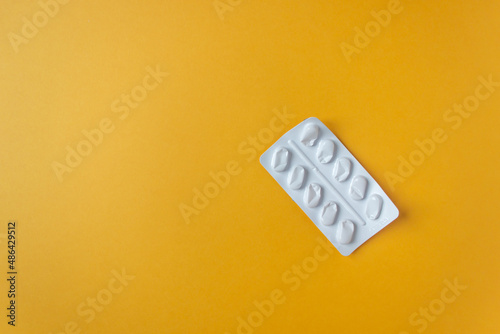 Empty white capsule blister isolated on the yellow background Fototapeta