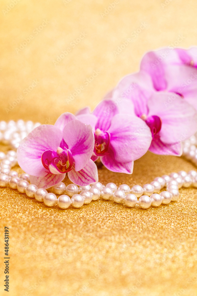 purple Orchid and pearl necklace on a shiny gold background purple Orchid and pearl necklace on a shiny gold background