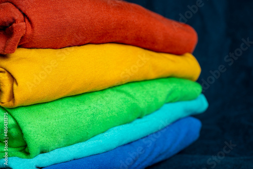 A stack of multicolored fabric without inscriptions. Background with folded clothes. T-shirts of different colors © Николай Батаев