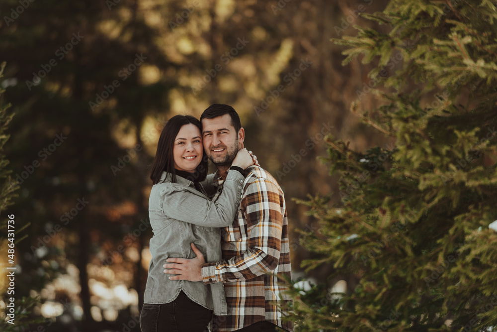 Fototapeta premium Portrait of handsome man hugging his loving wife on a winter day. Selective focus.