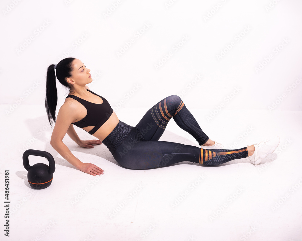 Strong fitness woman sitting on the floor isolated on white