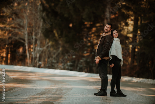 Loving couple standing back to back in winter on the background of a snowy highway. Selective focus. photo