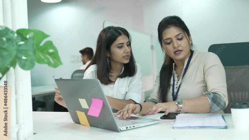 Focused millennial Indian leader helping new worker with laptop corporate software application in office. Motivated young Asian mixed race employees developing project growth strategy. Focused millennial Indian leader helping new worker with laptop corporate software application in office. Motivated young Asian mixed race employees developing project growth strategy.