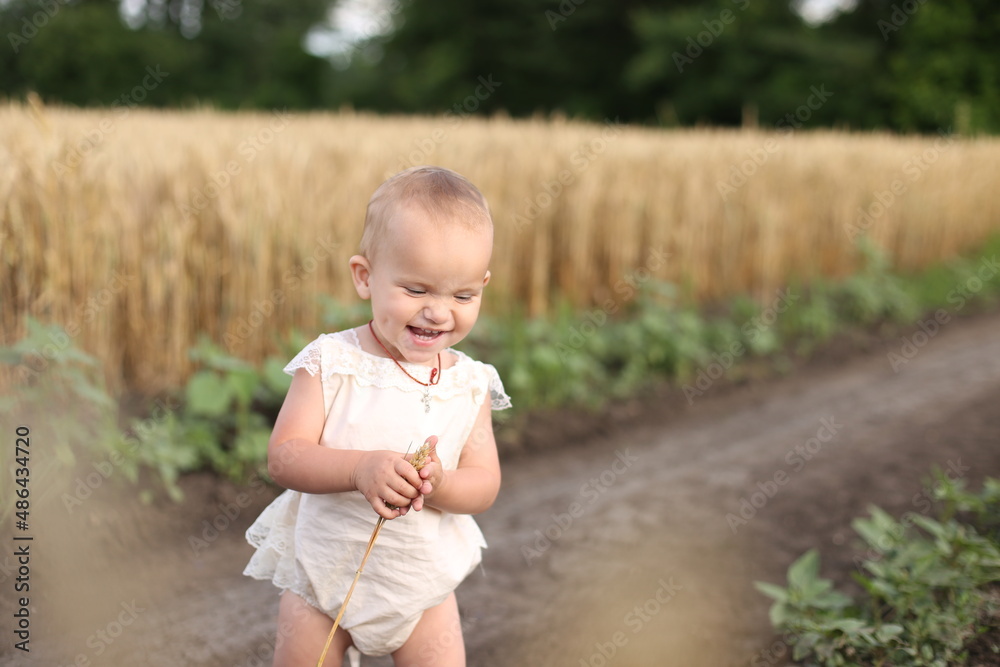 Little happy girl runs along the dusty road of a wheat field Little happy girl runs along the dusty road of a wheat field