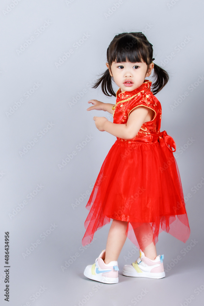 Studio full body shot of little cute innocent kindergarten preschooler girl daughter in traditional oriental red qipao cheongsam dress looking aside celebrate Chinese new year on gray background Studio full body shot of little cute innocent kindergarten preschooler girl daughter in traditional oriental red qipao cheongsam dress looking aside celebrate Chinese new year on gray background