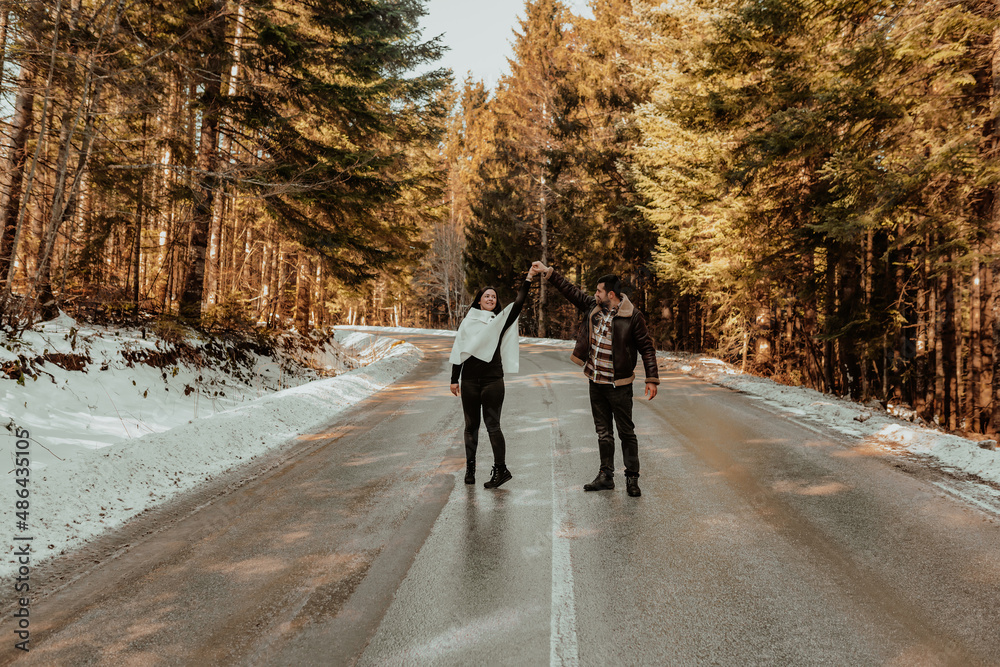 Attractive cheerful couple life partners in cozy winter days, dancing and kissing on a background of snowy highway. Selective focus. Attractive cheerful couple life partners in cozy winter days, dancing and kissing on a background of snowy highway. Selective focus.