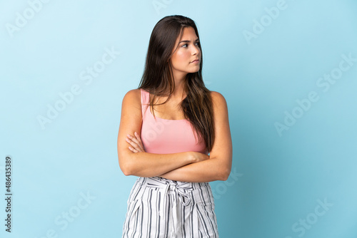 Young brazilian woman isolated on blue background looking to the side