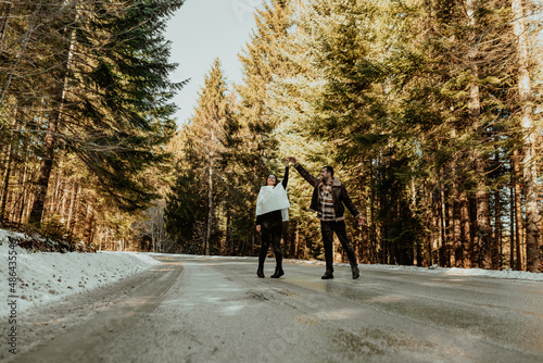 Attractive cheerful couple life partners in cozy winter days, dancing and kissing on a background of snowy highway. Selective focus. photo