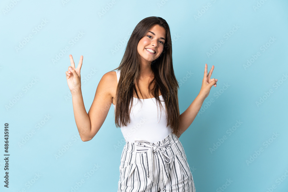 Young brazilian woman isolated on blue background showing victory sign with both hands Young brazilian woman isolated on blue background showing victory sign with both hands