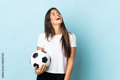 Young football player brazilian girl isolated on blue background laughing © luismolinero