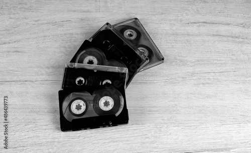 Black and white photograph of audio cassettes on a wooden background