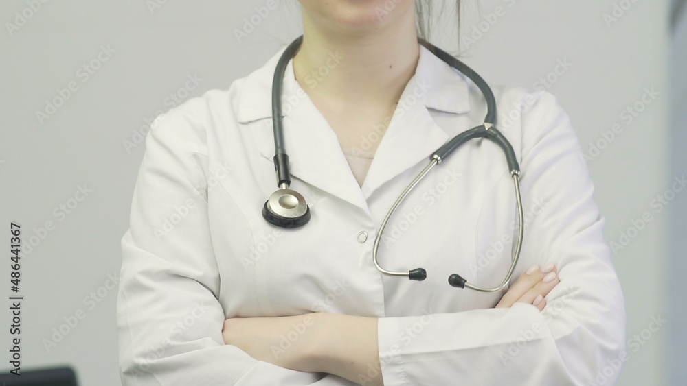 Close-up of a doctor a woman in a medical gown puts a stethoscope on her neck Close-up of a doctor a woman in a medical gown puts a stethoscope on her neck