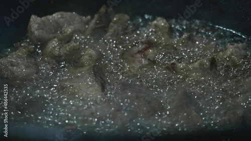 Close up view of meat being fried in a big cauldron. Cooking pilaf