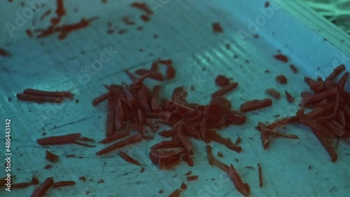 Slow motion of cook's hands removing grated carrot from table.