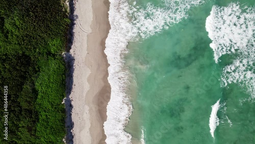 Straight down drone shot of white capped waves crashing over the beach in Jensen Beach Florida, Marine life surfaces over reef in Atlantic Ocean. Background of moving beautiful green water. photo