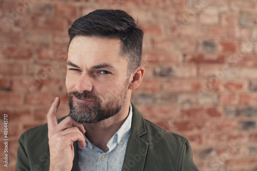 sassy flirty bearded middle-aged caucasian man giving the camera the eye over brick wall background. High quality photo © PoppyPix