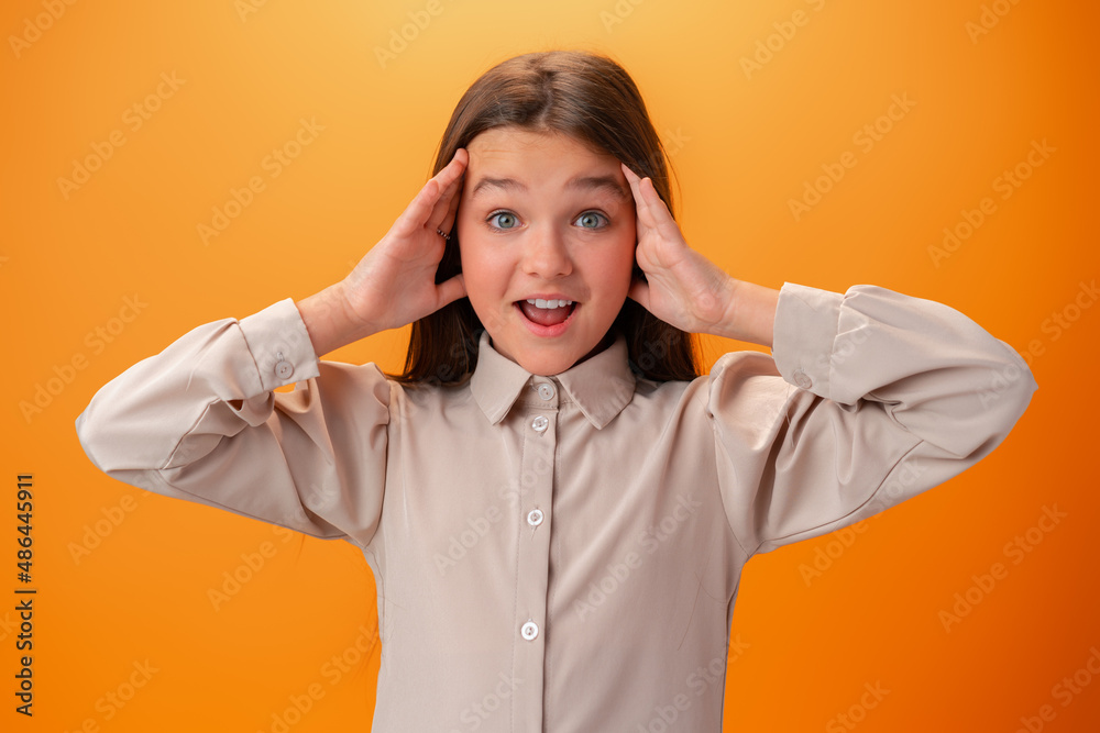 Shocked joyful teen girl against orange background Shocked joyful teen girl against orange background