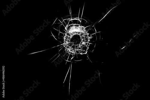Texture of broken glass. Hole from a ball on a black background.