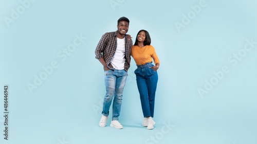 Confident couple standing and posing at blue studio background