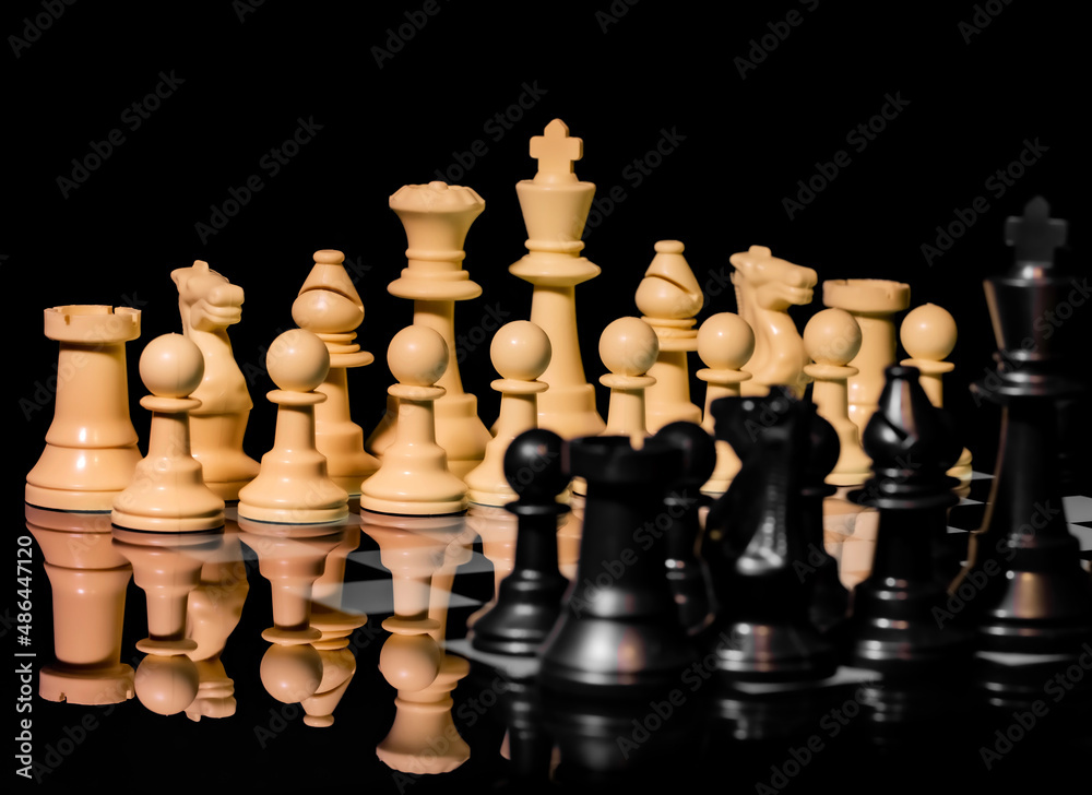 Close up of Chess pieces on a reflective mirror board surface with black background