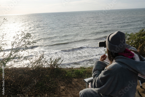 Young woman takes a photo on a smartphone of the seascape
