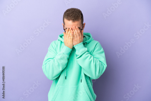 Young handsome caucasian man isolated on purple background with tired and sick expression