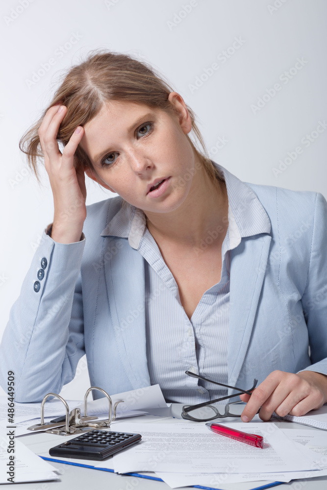 young business woman is doing paper work at desk and looks tired young business woman is doing paper work at desk and looks tired
