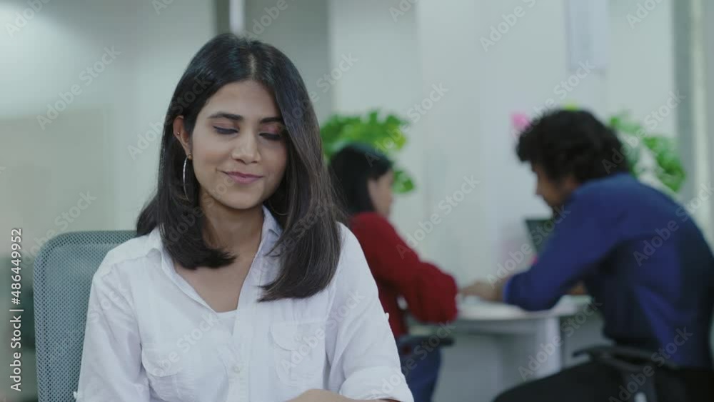Indian woman sitting on table while using smart phone for chatting with friends, family at home, office. smiling girl sitting on office desk and texting message on mobile phone. Indian woman sitting on table while using smart phone for chatting with friends, family at home, office. smiling girl sitting on office desk and texting message on mobile phone.