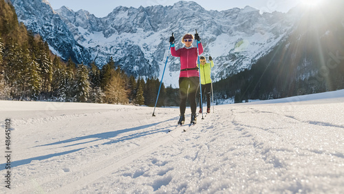 Foto Caucasian couple moving in sync while cross country skiing on the ski trail surrounded by mountains and forest