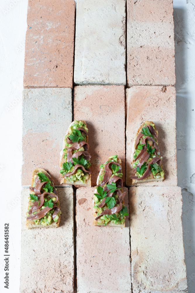 Baguette de anchoas de aguacate sobre ladrillos. Avocado anchovy