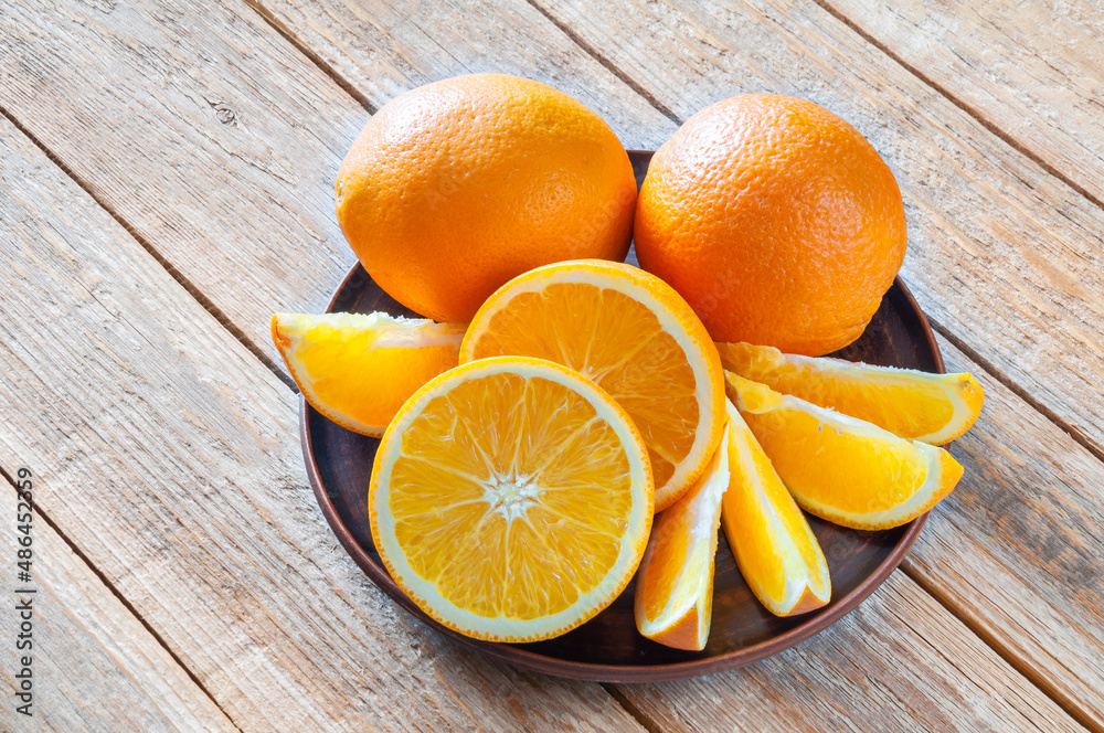 Plate with fresh oranges on wooden table Plate with fresh oranges on wooden table