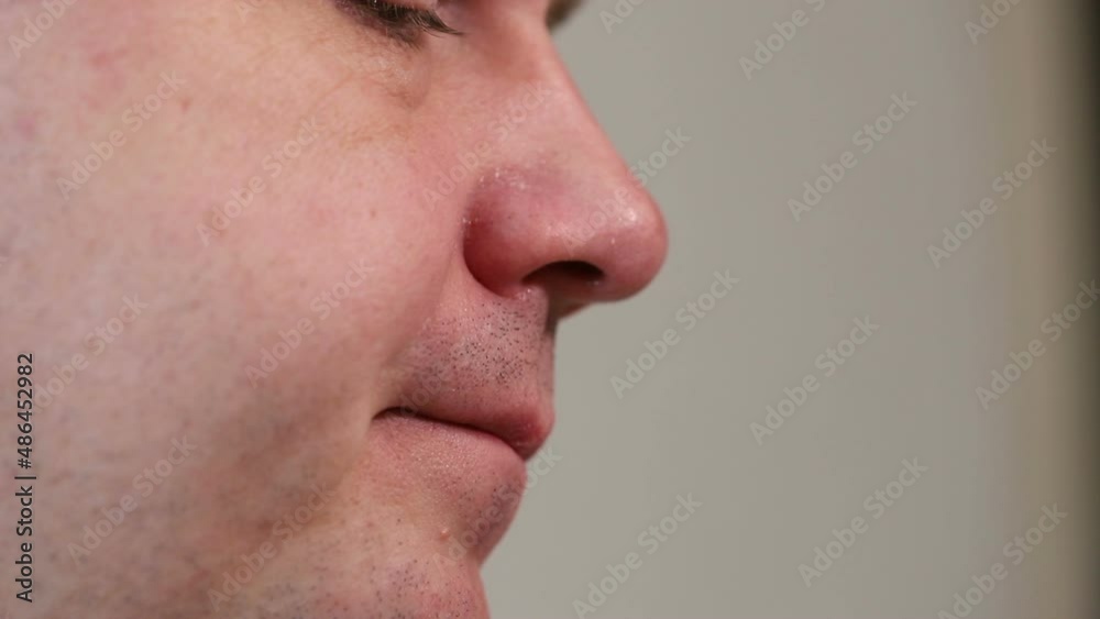 young european man pulls nose hair out with tweezers. close-up macro shot young european man pulls nose hair out with tweezers. close-up macro shot