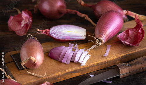 Photos Sliced Red tropea onions with a knife on a wooden board close up
